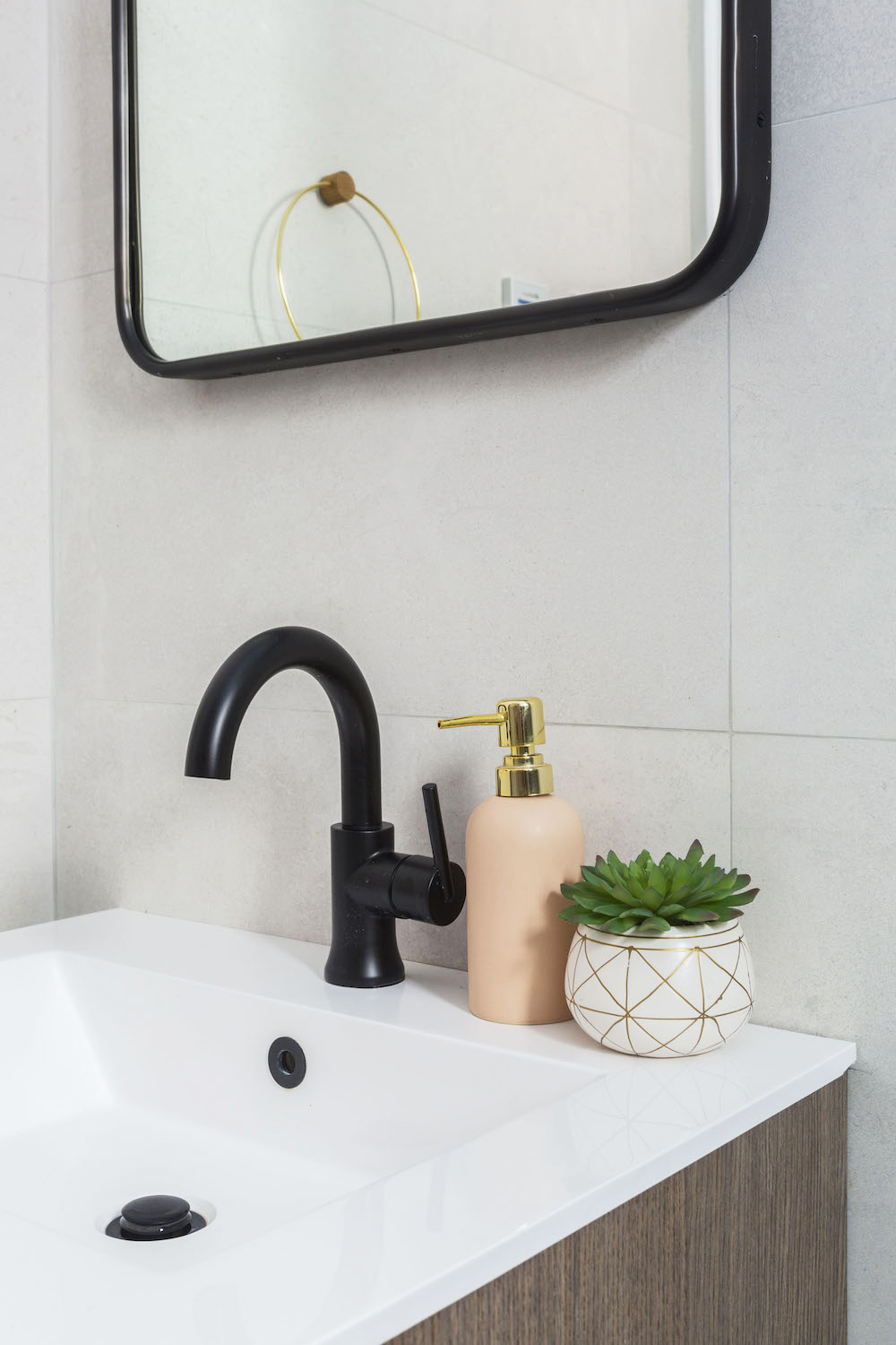 single wooden vanity with black faucet and mirror and off-white wall tiles after renovation