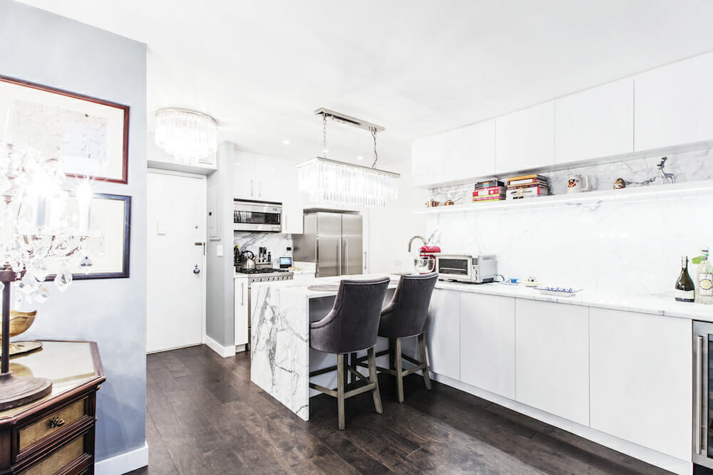 White kitchen with Calacatta marble countertop, white cabinets, and warm wood flooring
