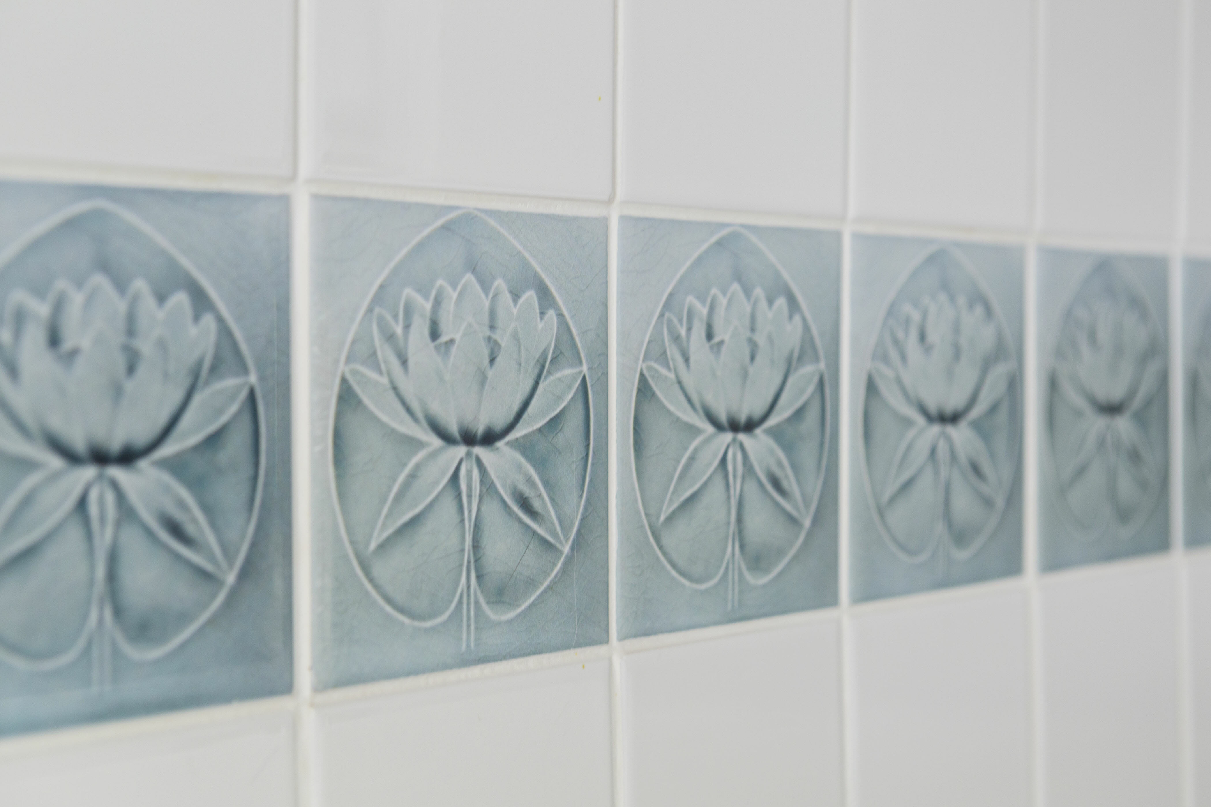 white tiles on wall with green lotus tile trim after renovation