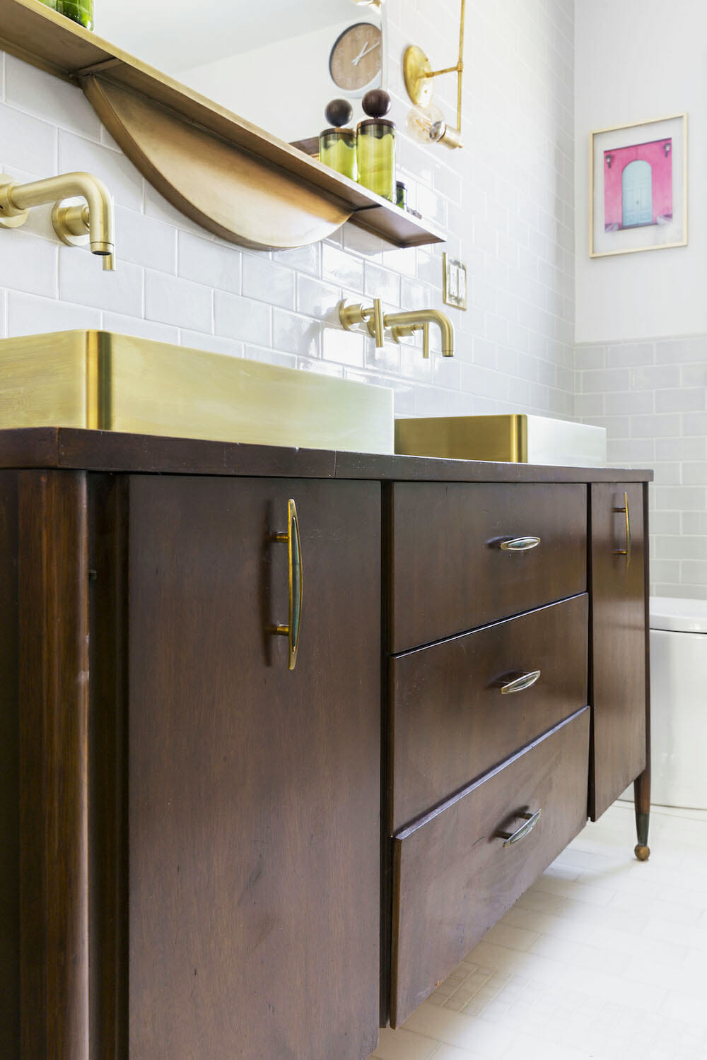 walnut double vanity with rectangle gold basin sink and gold faucets and fixtures and floating shelf after renovation 