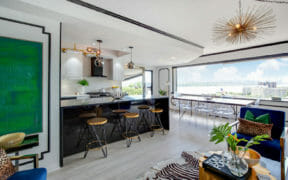 open kitchen with waterfall peninsula island  and large window in dining and white walls with picture frame molding after renovation