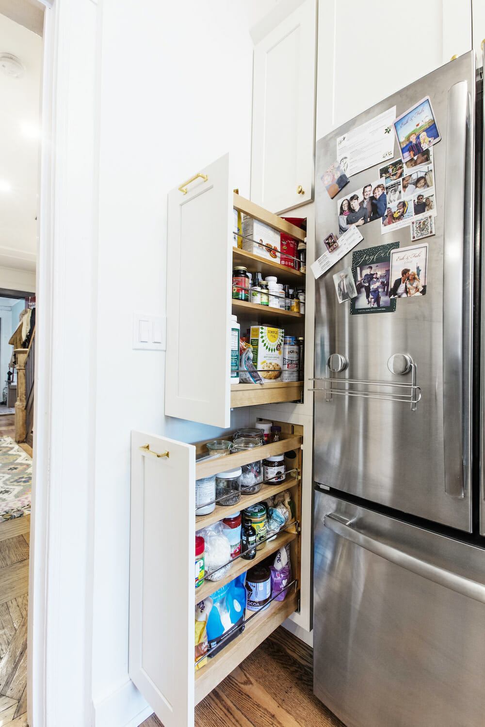white kitchen cabinets wrapping around refrigerator and pull-out pantry or cabinets after renovation