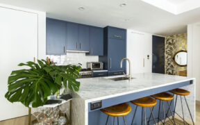 kitchen with navy blue cabinets and peninsula island with marble countertop and undermount sink with faucet after renovation