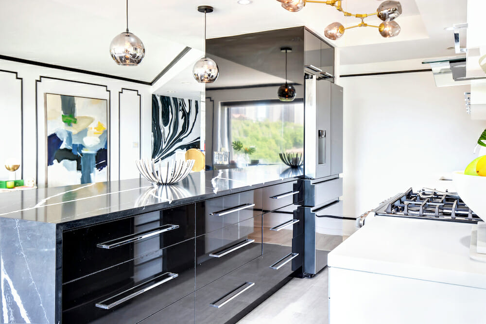 kitchen waterfall peninsula island with black marble countertop and black cabinets and pendant lights after renovation 