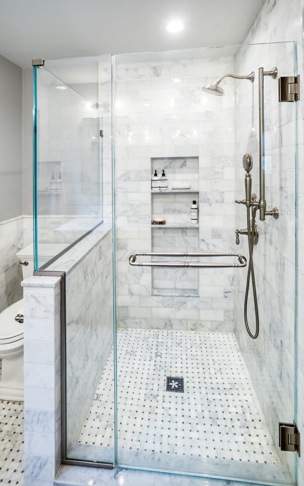 walk in shower with built in shelves and marble wall tiles and patterned floor tiles after renovation