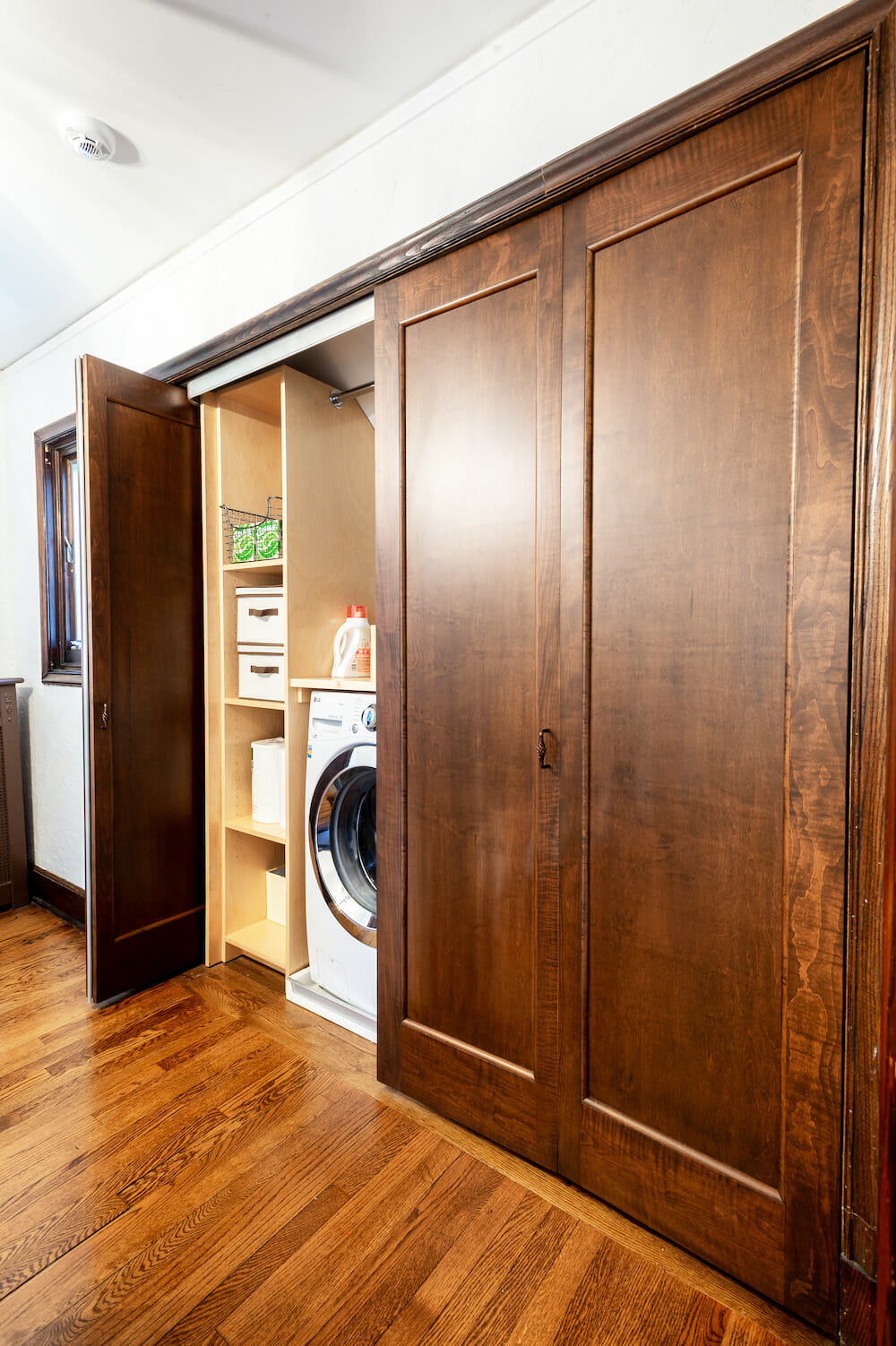 hallway laundry with storage and folding doors and hardwood floors in the hallway after renovation