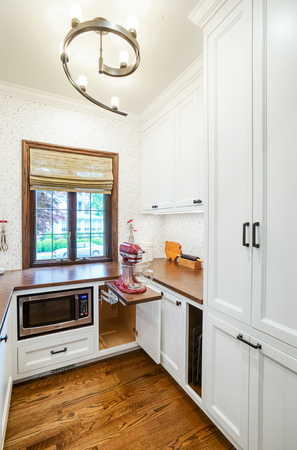 white kitchen cabinets with integrated under the counter microwave and hardwood floors after renovation