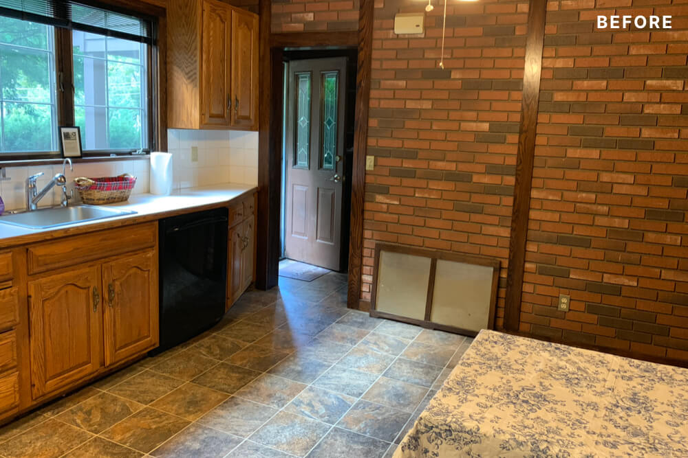 kitchen with oak cabinets and floor tiles and brick wall before renovation