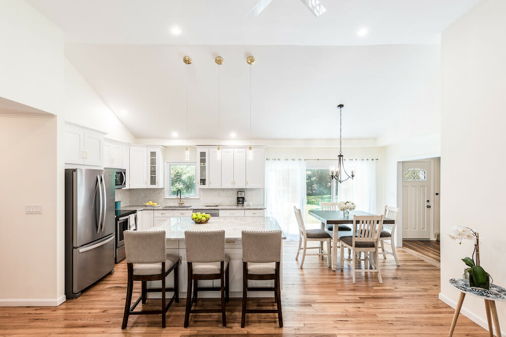 open kitchen and dining with white walls and hardwood floors and kitchen island with pendant lights and recessed lightting after renovation