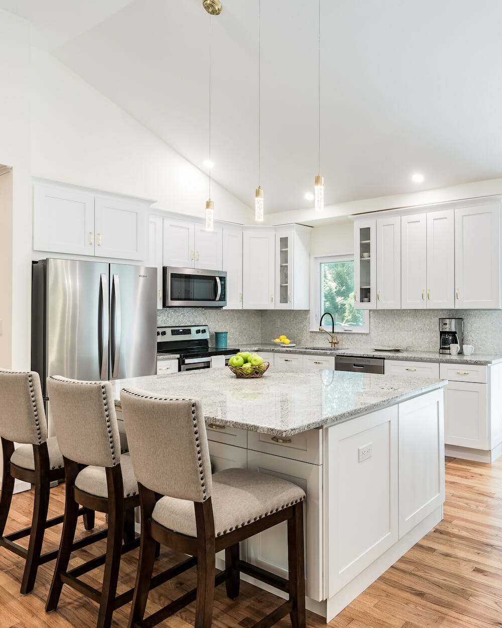 marble countertop on kitchen island with white cabinets and brown vinyl flooring after renovation