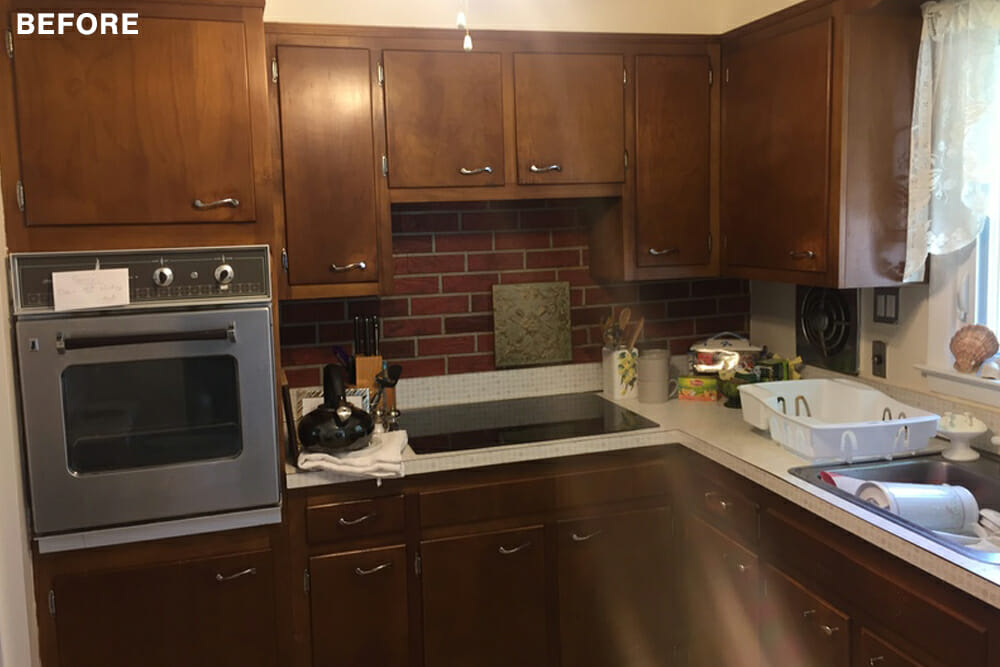 walnut cabinets with brick backsplash and built-in conventional oven before renovation