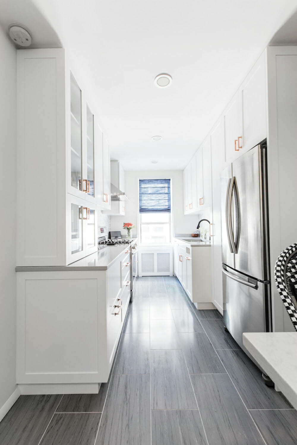 white kitchen cabinets with dark gray tile flooring and white paint on walls and flush mounted ceiling light after renovation
