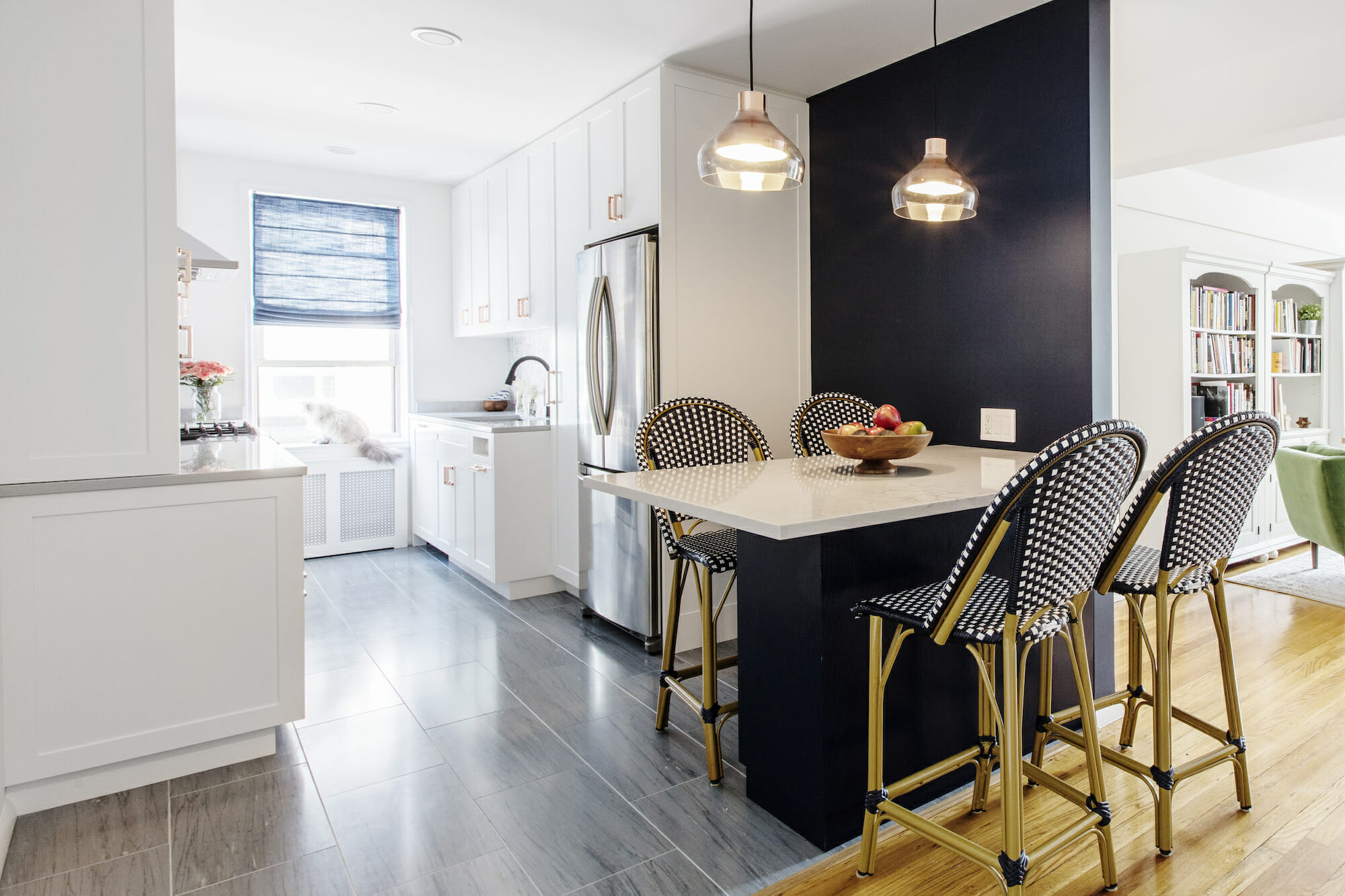 kitchen peninsula island with marble countertop and black base and black partition wall to the living room and pendant lights and hardwood look floor tiles after renovation