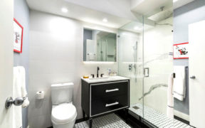 Black sink vanity with legs on white sink in a white and black bathroom after renovation