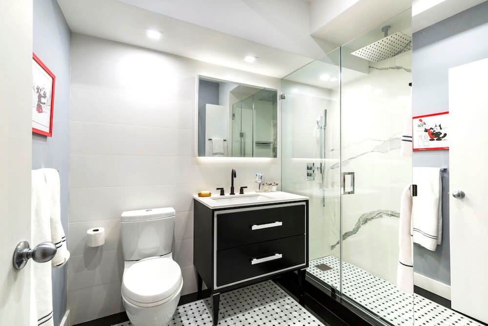 Black sink vanity with legs on white sink in a white and black bathroom after renovation