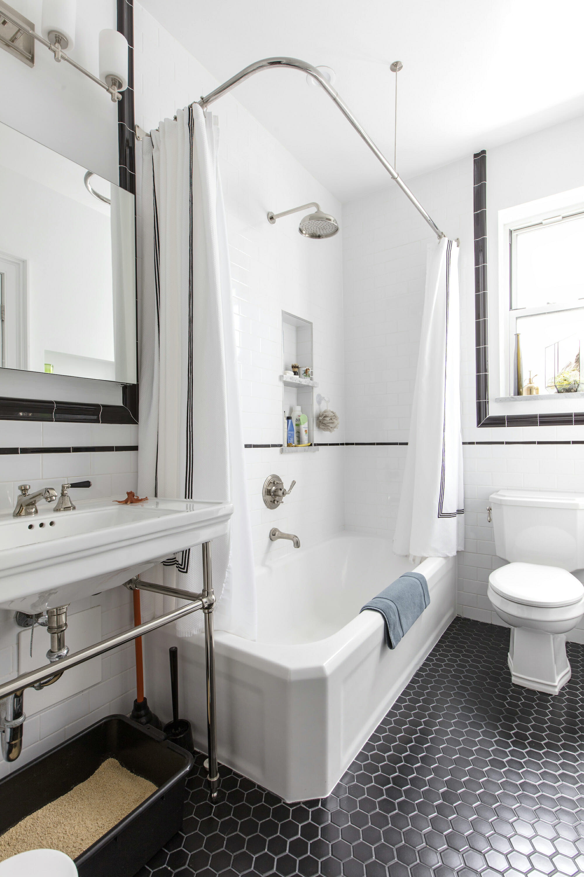Black and white tile bathroom in Upper Manhattan with tub and shower, white sink, and toilet