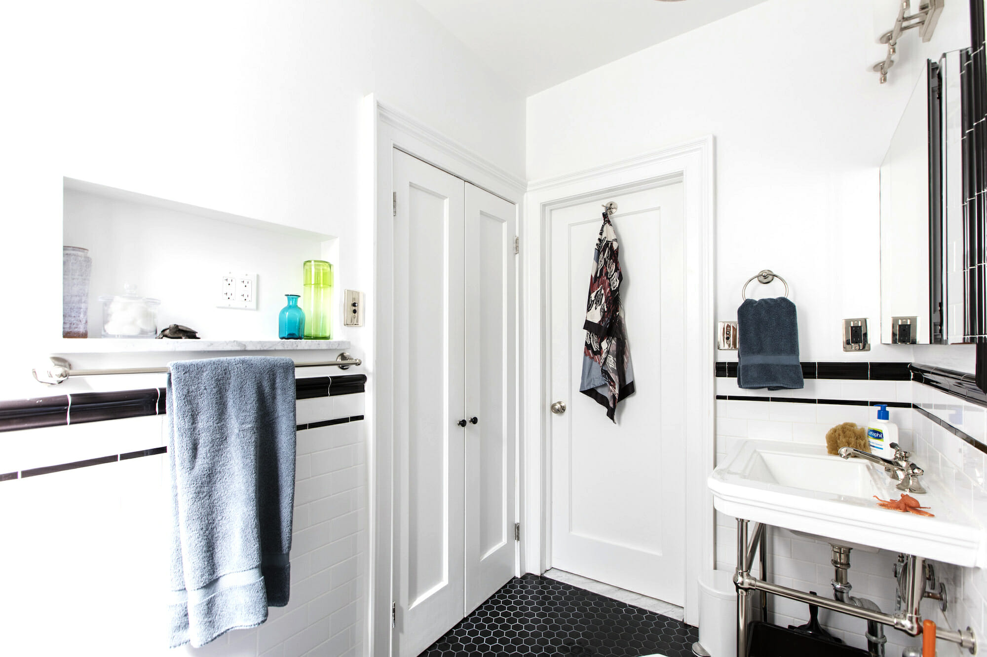 Matte black hex tile floor, white walls and doors, and hanging towel