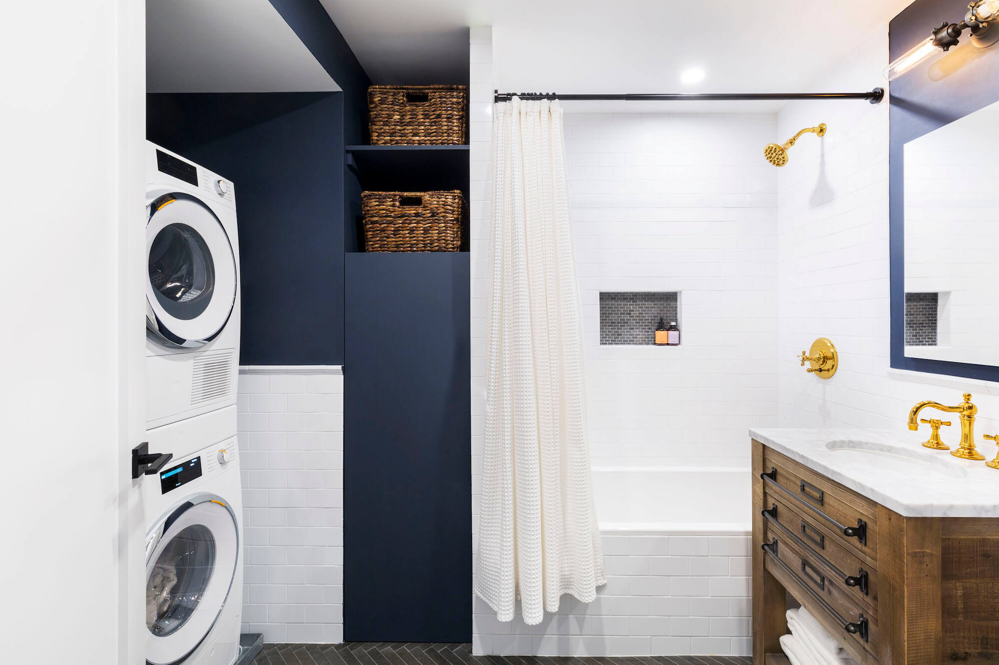 White subway tiles and blue paint in bathroom and laundry niche with washer dryer after renovation