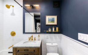 Navy blue paint and white subway tiles and brass fittings over white bathtub after renovation