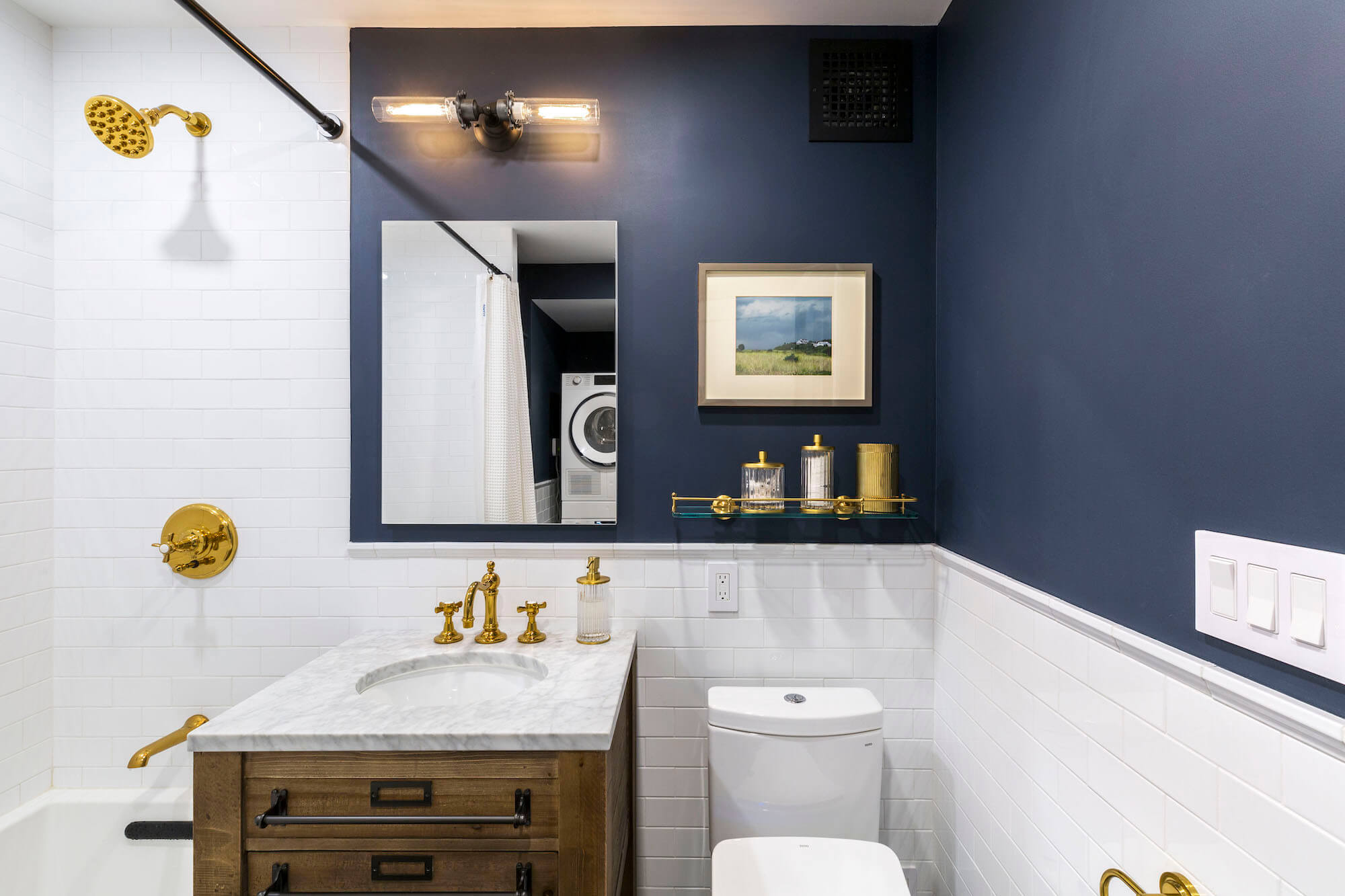Navy blue paint and white subway tiles and brass fittings over white bathtub after renovation