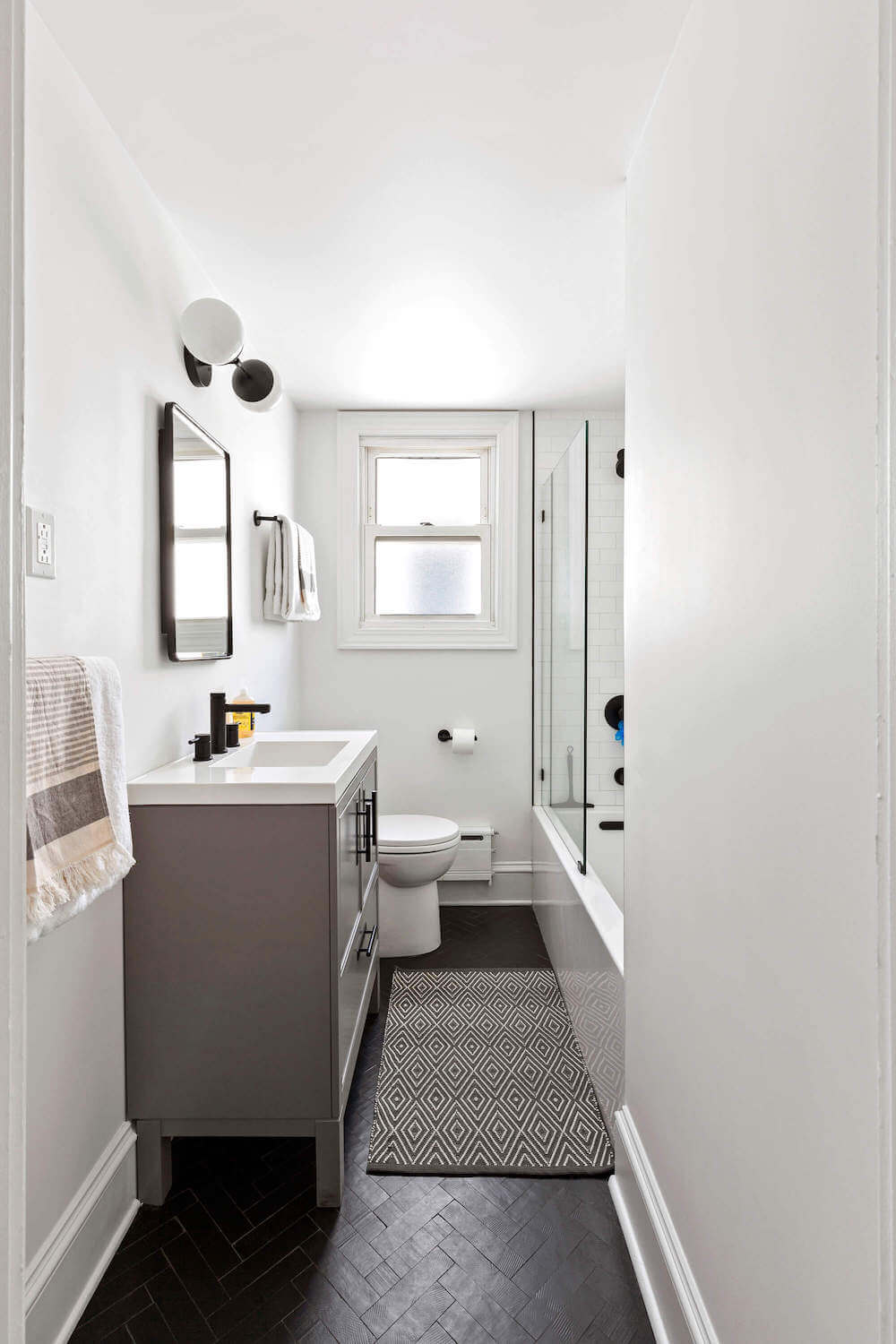 gray bathroom vanity with black herringbone floor tile