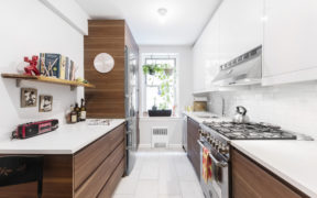 white and wood kitchen cabinets and stainless steel appliances and tile flooring after renovation