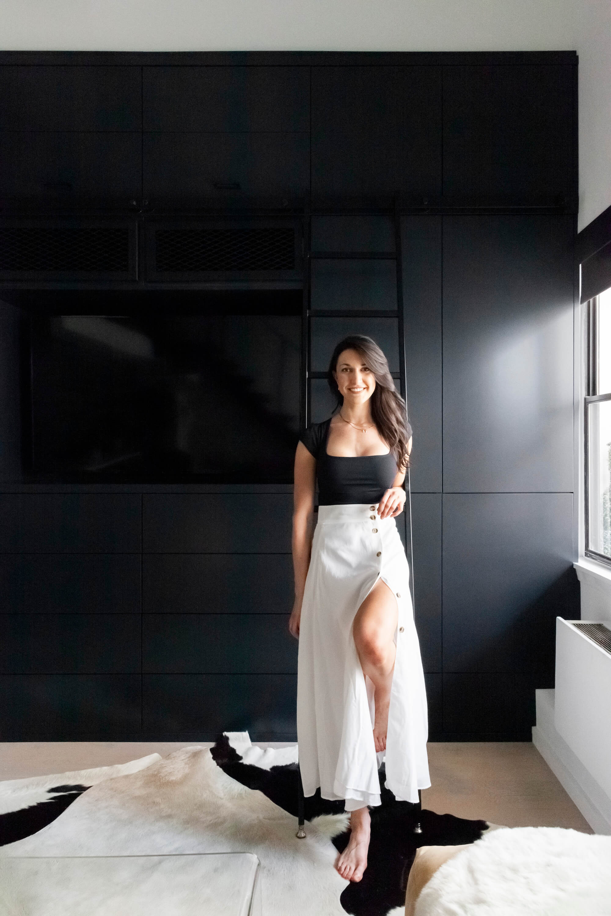 photo of carly standing in front of a black accent wall after renovation