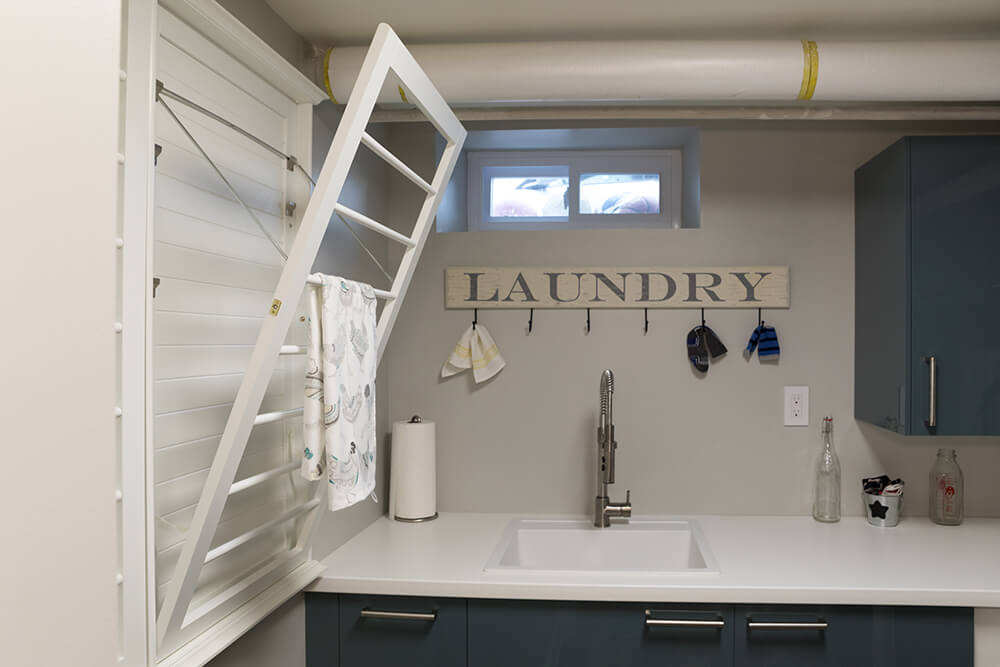 White and gray laundry space with sink and white quartz countertop and retractable laundry airer after renovation