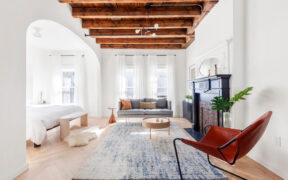 Living area of Brooklyn brownstone with exposed wooden beams and an alcove bedroom