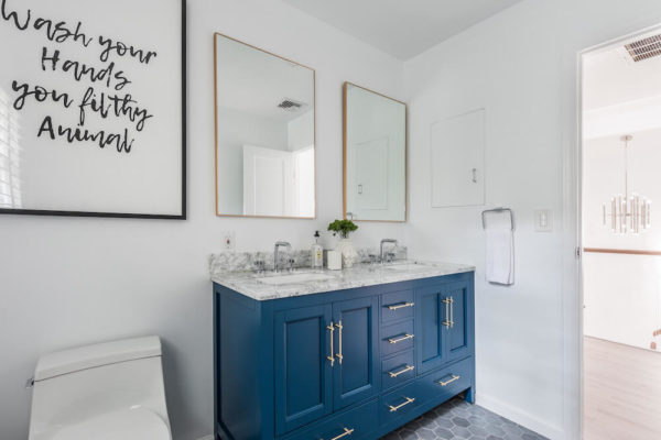 white double sink and blue vanity with cabinets and double mirror after renovation