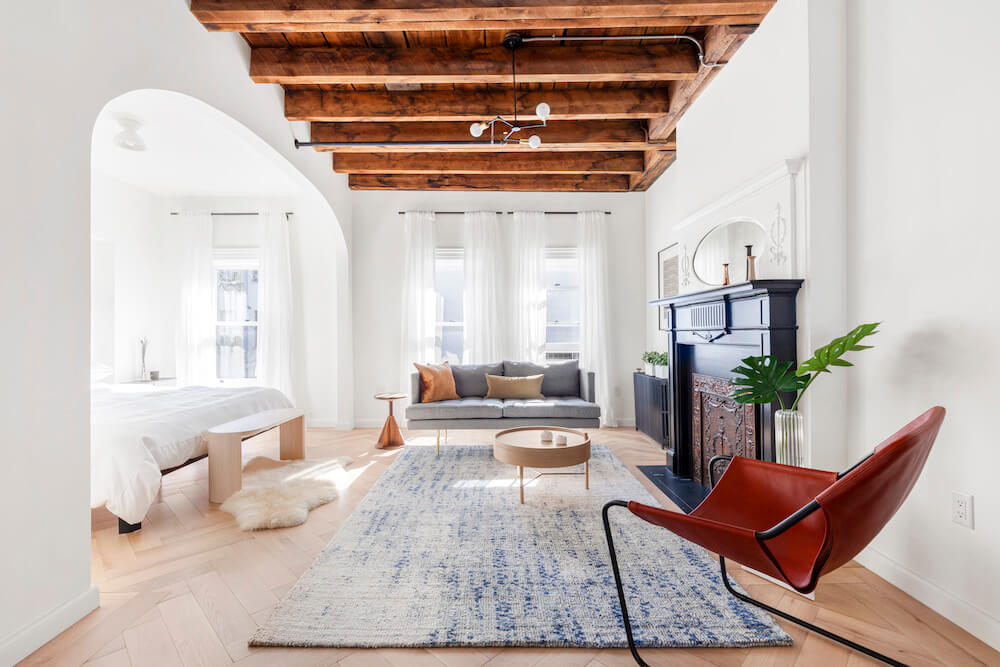 Living area of Brooklyn brownstone with exposed wooden beams and an alcove bedroom