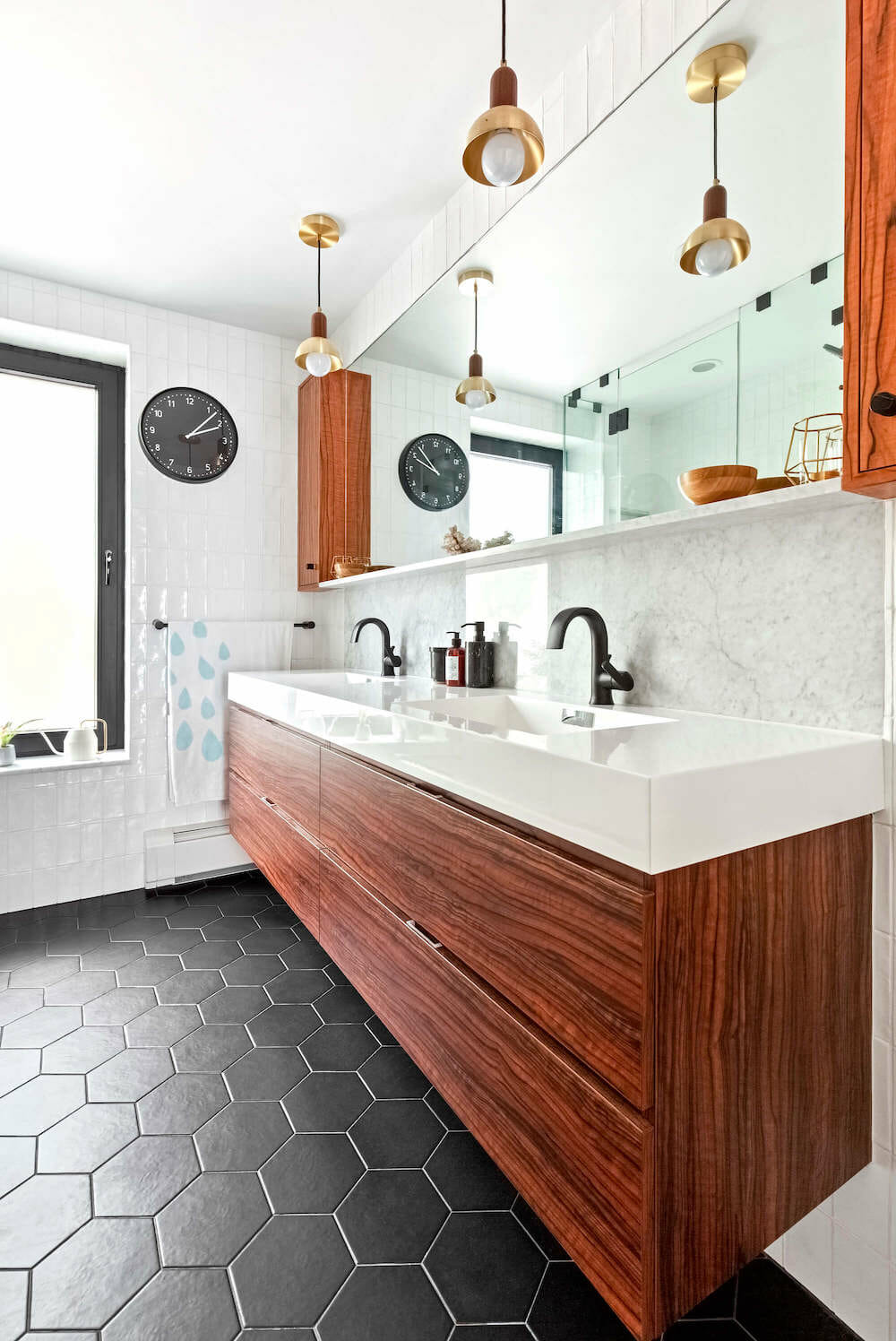 black hexagon floor tiles with brown floating vanity and white double sink and long wide mirror vanity after renovation