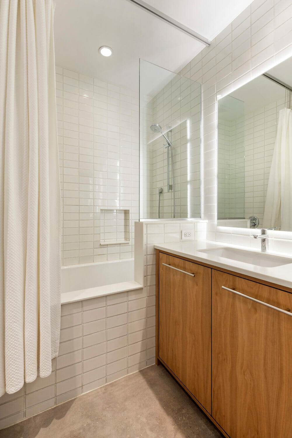 Bathroom with a white subway tile soaking tub and poured concrete floor