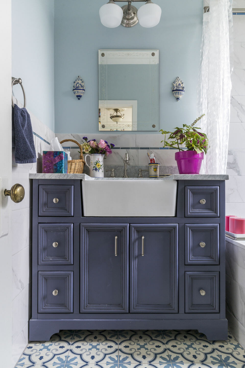 patterned blue floor tiles under powder blue bathroom vanity and a large farmhouse white sink after renovation