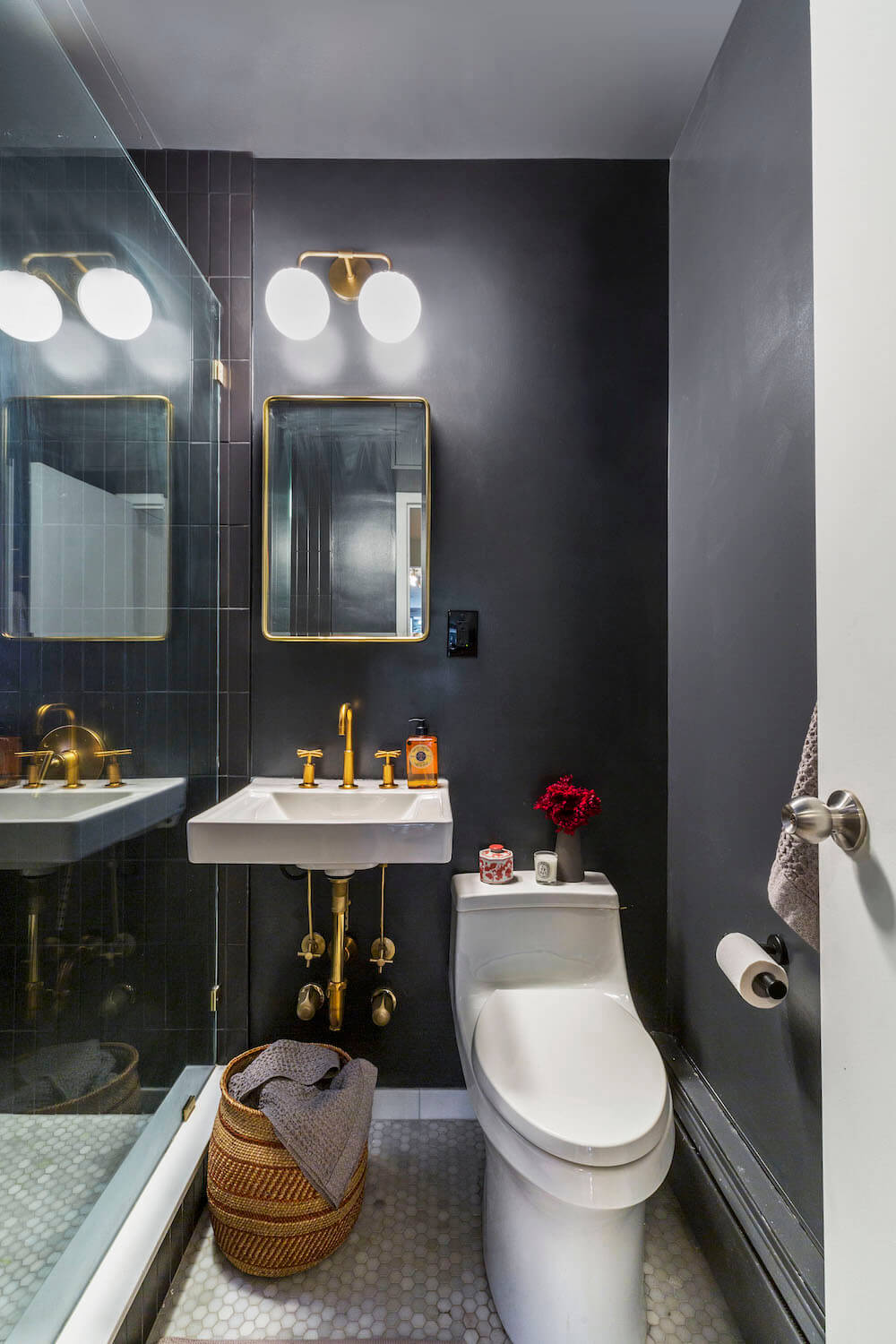 small black bathroom with white toilet and glass separator for shower area after renovation