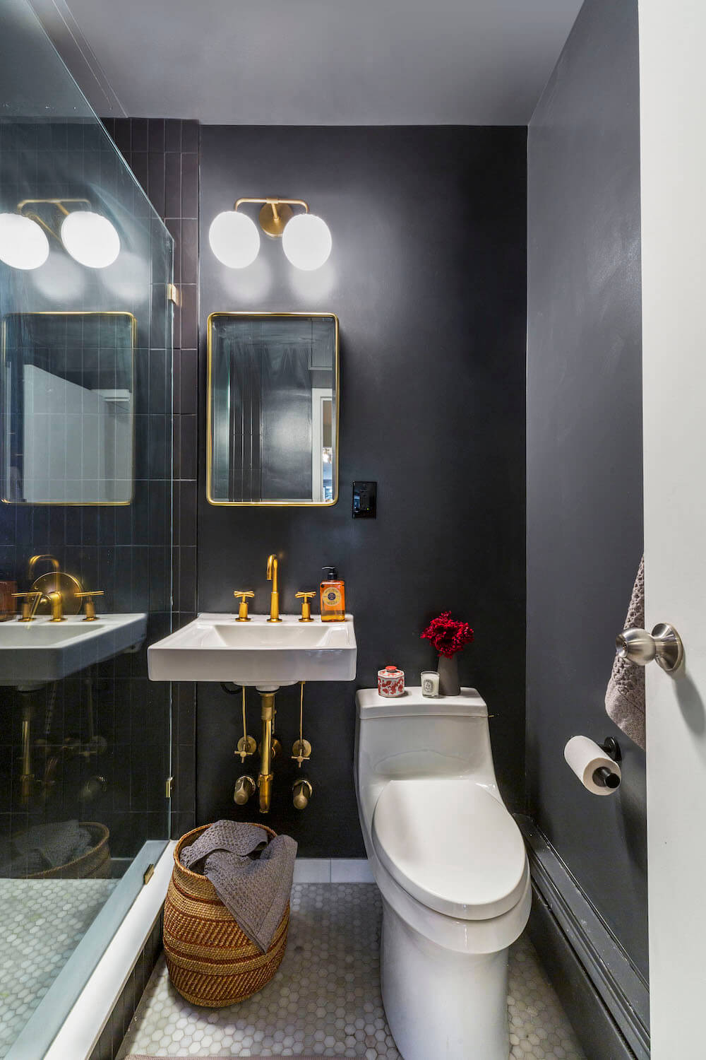bathroom with floating sink and gold faucet and fixtures and black paint on wall and walk-in shower with glass wall after renovation