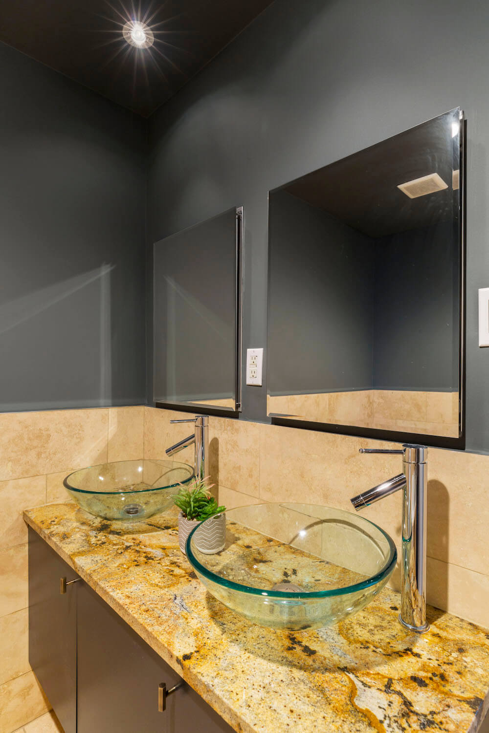 double glass vessel basin sink vanities with mirrors and granite countertop and dark bathroom walls after renovation