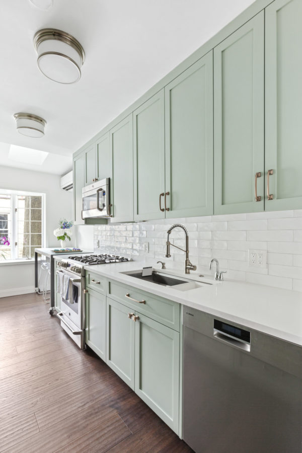 sea green kitchen cabinets with white countertop and sink with steel faucet after renovation