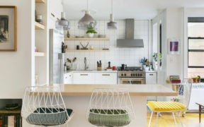 brown kitchen island with metal chairs and white subway tiled kitchen and kitchen cabinets after renovation
