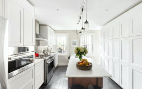 Kitchen with white floor-to-ceiling cabinets, dark hardwood floors, and white countertop kitchen island
