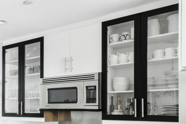 black framed glass kitchen cabinets in a white walled kitchen after renovation