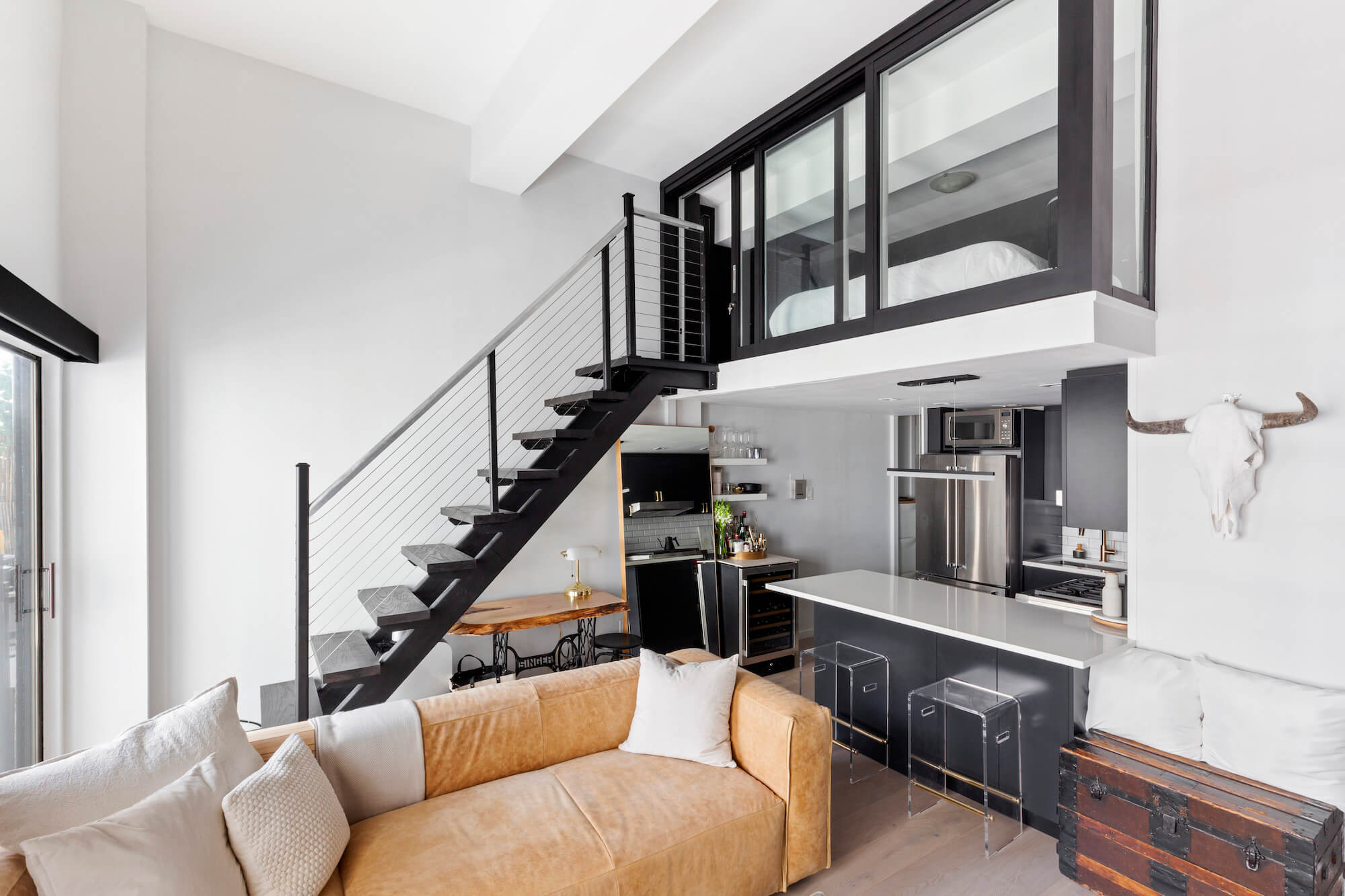 black industrial stairs leading to a living room with orange couch after renovation