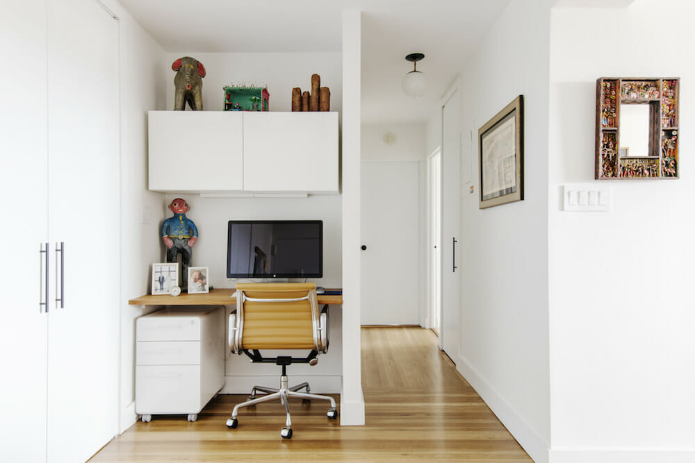light wooden floor in a white bedroom with tiny study nook with white cabinets after renovation
