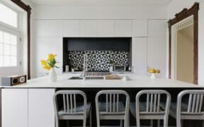large white kitchen island with black geometric backsplash after renovation
