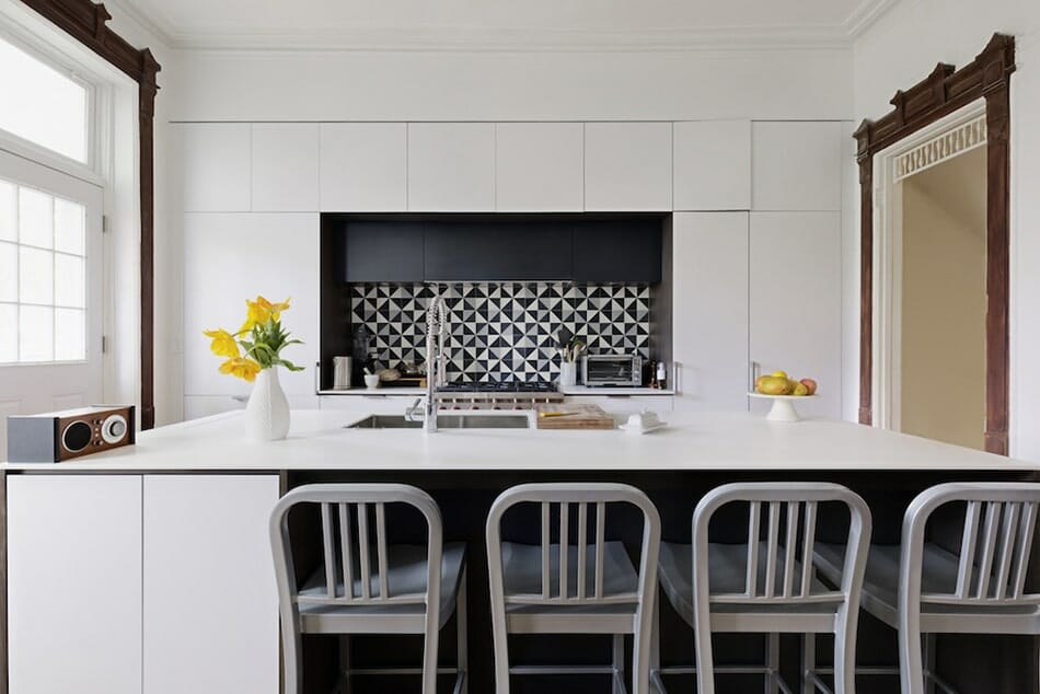 large white kitchen island with black geometric backsplash after renovation