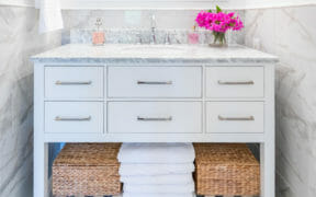 white vanity with marble top and drawers and marble tiles on bottom half of the walls after renovation