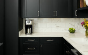 black kitchen cabinets with nickel handles and marble countertop and backsplash and undermount sink after renovation