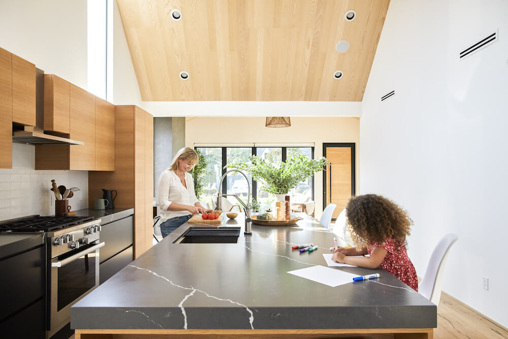 Candid photo of mom and daughter hanging out at the kitchen island in their renovated LA home