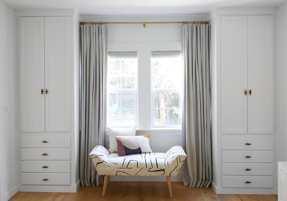 custom built-in closets in bedroom with lounging bench by window