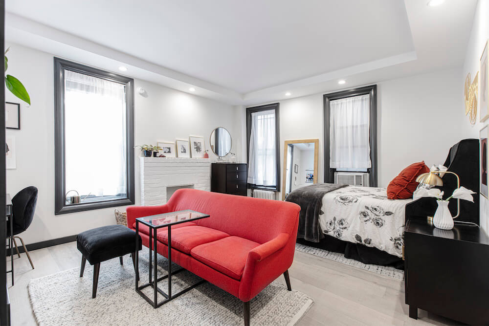 Modern living room in studio apartment with bold red sofa and black accents